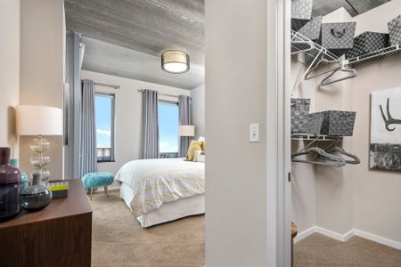 Furnished model bedroom with a walk-in closet and concrete ceilings