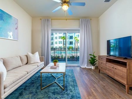 m2 at millenia living room with patio door, ceiling fan with light and wood vinyl flooring