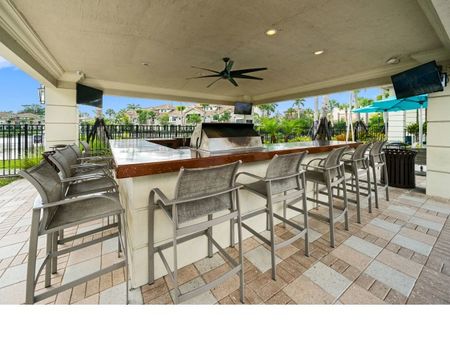 Outdoor bar with grille with three televisions and a ceiling fan