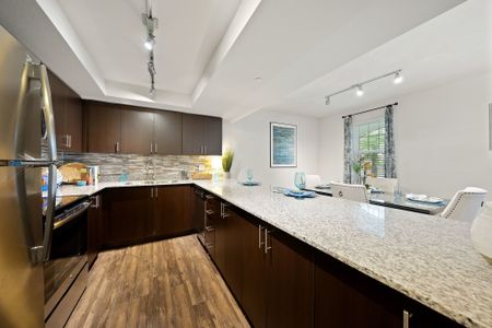 Kitchen with tile back splash and stainless steel refrigerator and oven overlooking dining room
