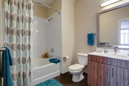 Bathroom with tiled shower and garden tub. Toilet positioned between shower and vanity. Vanity with cabinets beneath and silver framed mirror above.
