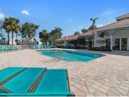 Swimming pool surrounded by chaise lounge chairs and patio tables with umbrellas