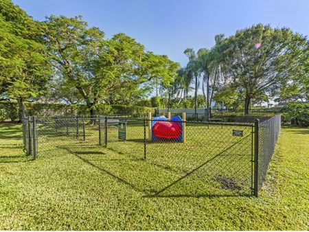 Fenced dog park with obstacles including a tunnel and jumps