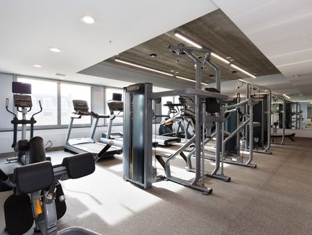 Renovated fitness center with exercise equipment and concrete ceilings