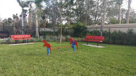 Grassy outdoor dog park with benches and agility obstacle