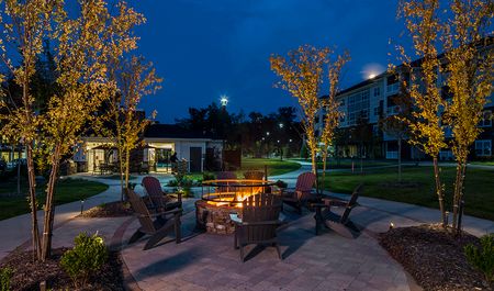 Evening view of gas fire pit and adirondack chairs on backside of village green
