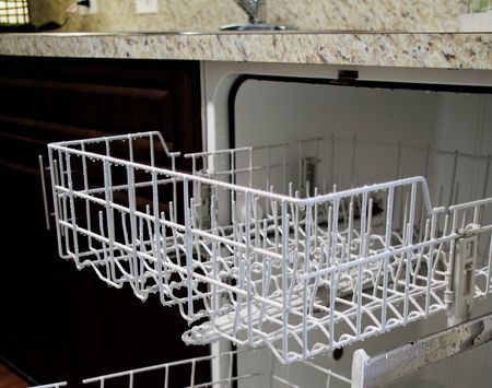 Close-up view of racks in dishwasher, built into kitchen with granite countertops