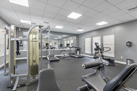 Fitness center with mirrored wall, treadmills, workout benches, and various weight machines