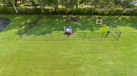Fenced dog park with obstacles including a tunnel and jumps