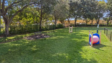 Fenced dog park with obstacles including a tunnel and jumps