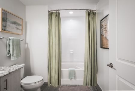 Apartment main bathroom with porcelain tile flooring, a walk-in shower with a glass door, and a bathtub with tile surround and recessed lighting