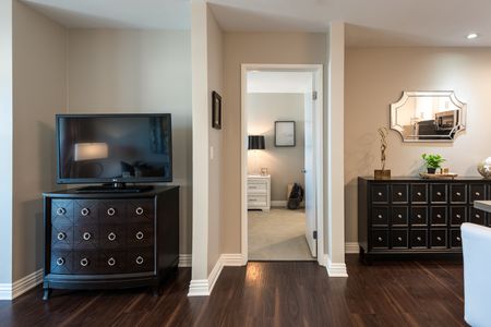 living room and entrance to bedroom with wood-inspired plank flooring an entertainment console with a television at the warwick