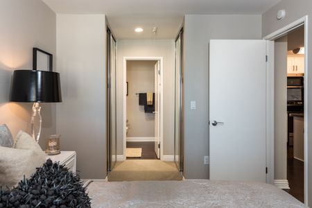 carpeted bedroom with mirrored closet doors and entrance to the bathroom at the warwick