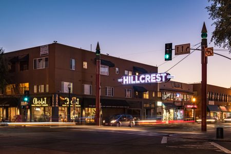 the hillcrest sign lit at night with cars driving through