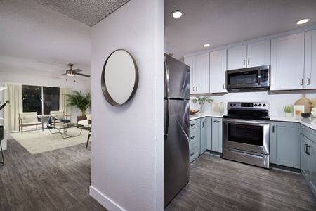 Virtually staged kitchen with updated appliances, cabinets, flooring and countertops and breakfast bar leading out to living room