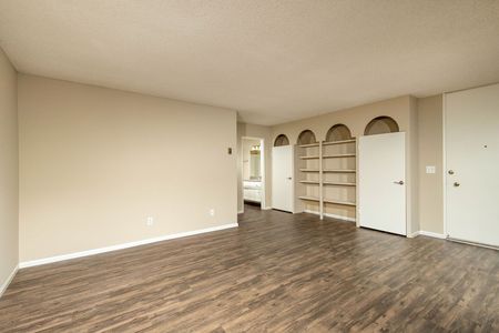 Large living area with built-in shelving and wood-inspired plank flooring