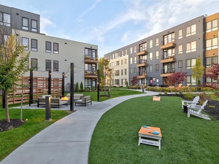 Sidewalks through landscaping with yard games, seating, and patio area | West End Yards | Apartments In Portsmouth, NH