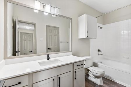 Interior bathroom with white granite countertop, white cabinets, and tub/shower combo.