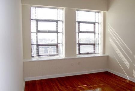 Living room with bright windows at Sydnor Flats Apartments