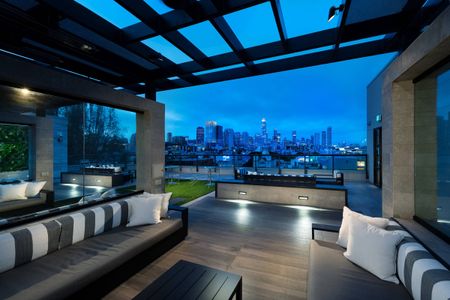 Rooftop open-air lounge with an overhead pergola structure, seating areas with couches, and a panoramic San Francisco skyline view.