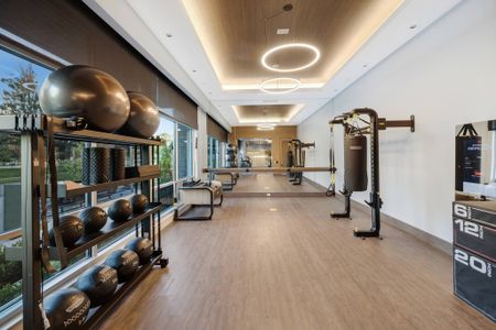 Indoor gym with windows, an Echelon Reflect Mirror, yoga space, machines and equipment.