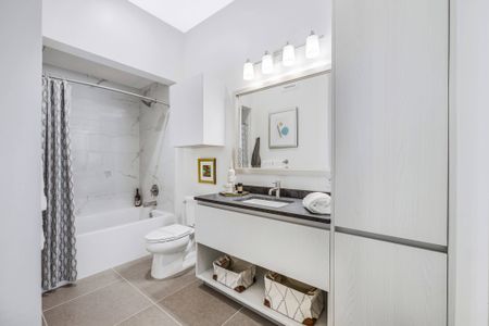 Bathroom with tile floors, a large soaking tub and white cabinetry with a storage shelf below the vanity.