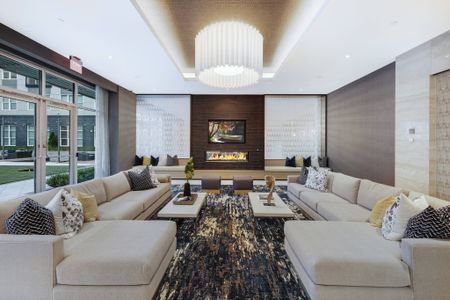 Resident clubhouse with two white couches, coffee tables, a flat-screen TV, fireplace, and floor-to-ceiling windows with an entrance to a courtyard.