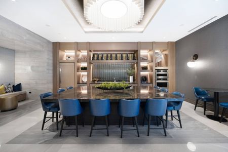 Catering kitchen with stainless steel appliances and a large brown marble island with blue barstools.