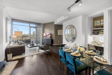 Large dining space with glass table and 6 dining chairs, with built-in desk and wide-plank wood-style flooring overlooking the living room and floor-to-ceiling windows
