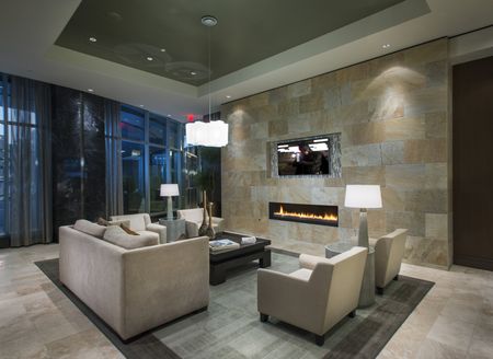 Seating area with floor-to-ceiling windows, stone floors and walls with an inset fireplace, an HDTV, four armchairs, and a loveseat.