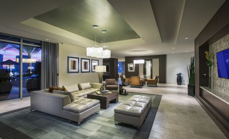 Lounge with floor-to-ceiling windows, a large leather sectional couch, a wall-mounted HDTV, and neutral colors.