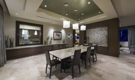 8-seat dining table with stone floors, modern light fixtures and decorations, and an adjacent catering kitchen