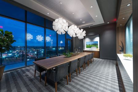 Dining room with a 12-person wood table, upholstered chairs, a buffet, and floor-to-ceiling windows and doors leading to a terrace with city views