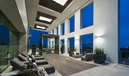 Open-air loggia with seating areas, upholstered lounge chairs, and skyline views