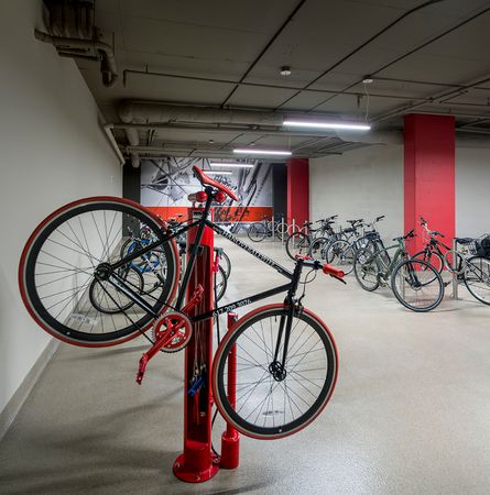 A garage-like room with bikes on stands along the walls and a bike hanging on a repair stand, which includes an air pump and other tools.