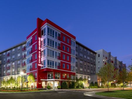 Exterior rendering of the Hanover Alewife apartment building showing a red, white and gray exterior and trees lining the sidewalk.