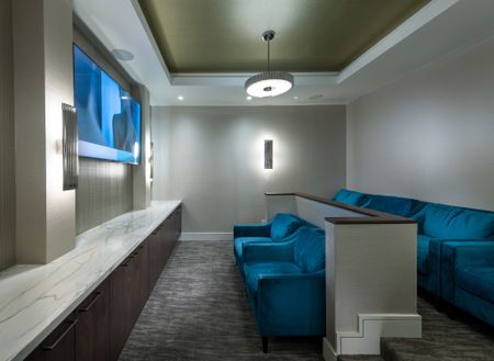 Theater with two elevated rows of plush blue upholstered loveseats facing a large HDTV screen.
