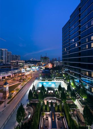 Aerial view of the 6th-floor pool deck, with tall landscaped trees in the foreground and the Midtown skyline in the background.