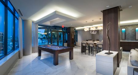 Alternate view of the lounge from next to the window, showing the billiards table, dining table, and a modern bronze statue of a slender human figure.