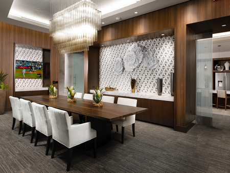 Dining room with 8-person wooden table, modern glass chandelier, HDTV, modern art, and wood-paneled walls with geometric mosaic insets.