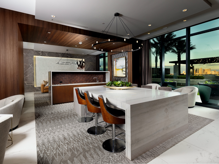 Clubhouse with dark wood-paneled walls, 6-seat marble dining table, wet bar, minimalist black chandeliers, armshairs around the walls, and floor-to-ceiling window overlooking the pool.