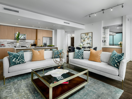 Open-concept living room with two large couches, a coffee table, dark wood-style floors, and white walls.