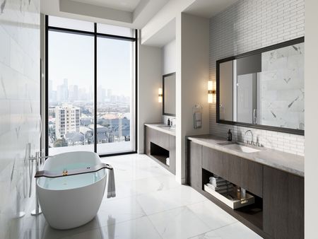 Penthouse bathroom with a freestanding tub, marble floors and walls, two large vanities with their own sink and mirror, and a floor-to-ceiling window with a skyline view.
