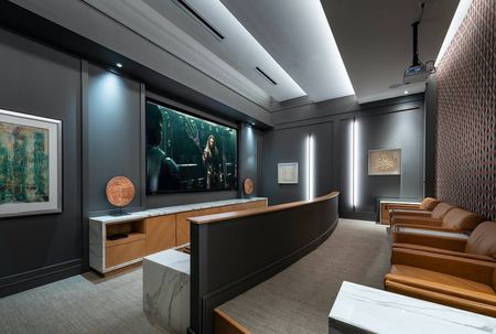 Private theater with a large projector screen and two tiered rows of large leather armchairs