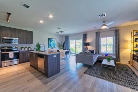 The Reserve at Coral Springs, interior, kitchen, living room, open concept, wood floor, dark cabinets, microwave, stove/oven, ceiling fan, dishwasher, sliding glass doors