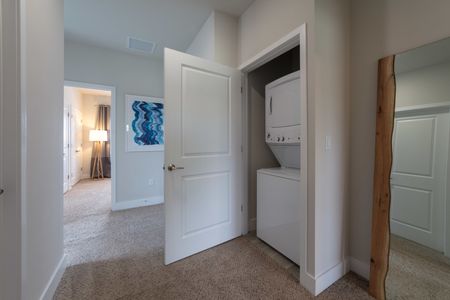 The Reserve at Coral Springs, interior, hallway closet laundry, stack-able white washer and dryer, carpeted floors