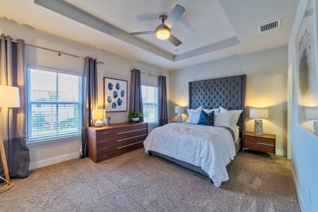 The Reserve at Coral Springs, interior, spacious carpeted bedroom, large windows, ceiling fan, bed, dresser, nightstand
