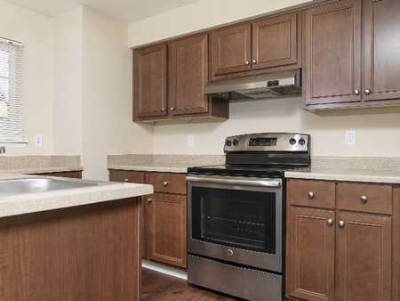 Updated Kitchens, Toffee Brown Cabinets, Mahogany Style Plank Floors and Stainless Steel Appliances Canyon Park l Luxury Remodeled Apartments in Puyallup