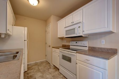 Coryell Crossing Apartments kitchen with white cabinets, white appliances and laminate floors