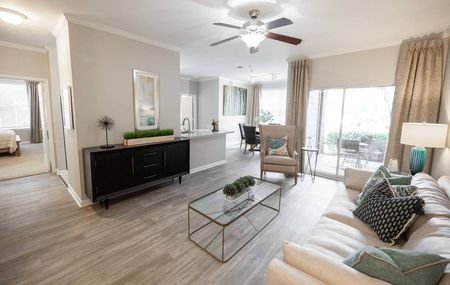 Luxury Apartments for Rent in Duluth, GA - Parc 85 - Furnished Living Room with Wood-Style Flooring, Ceiling Fan, and Sliding Glass Door to Patio.